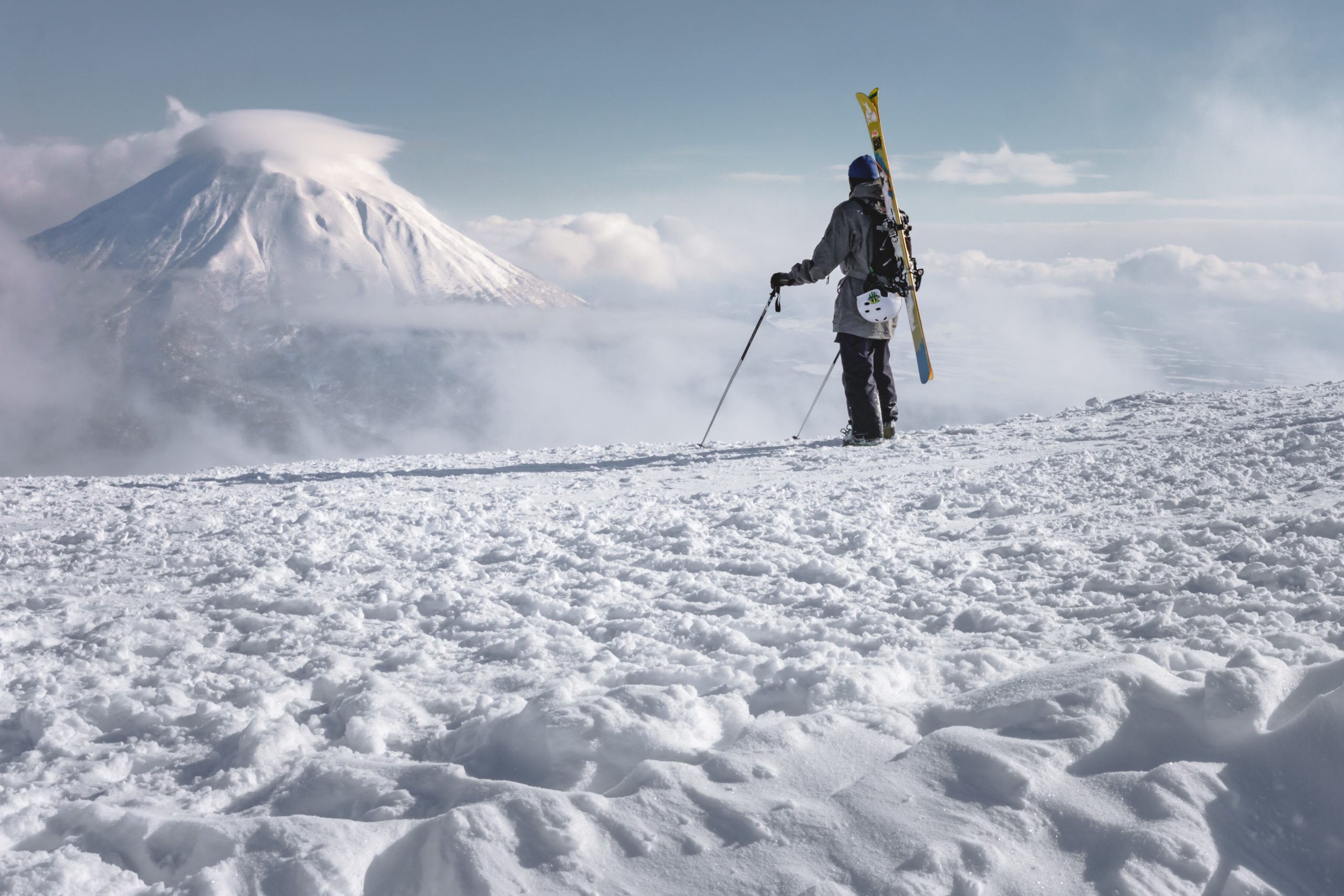 Skier hiking with skis on shoulder beneath Mount Yotei, Niseko