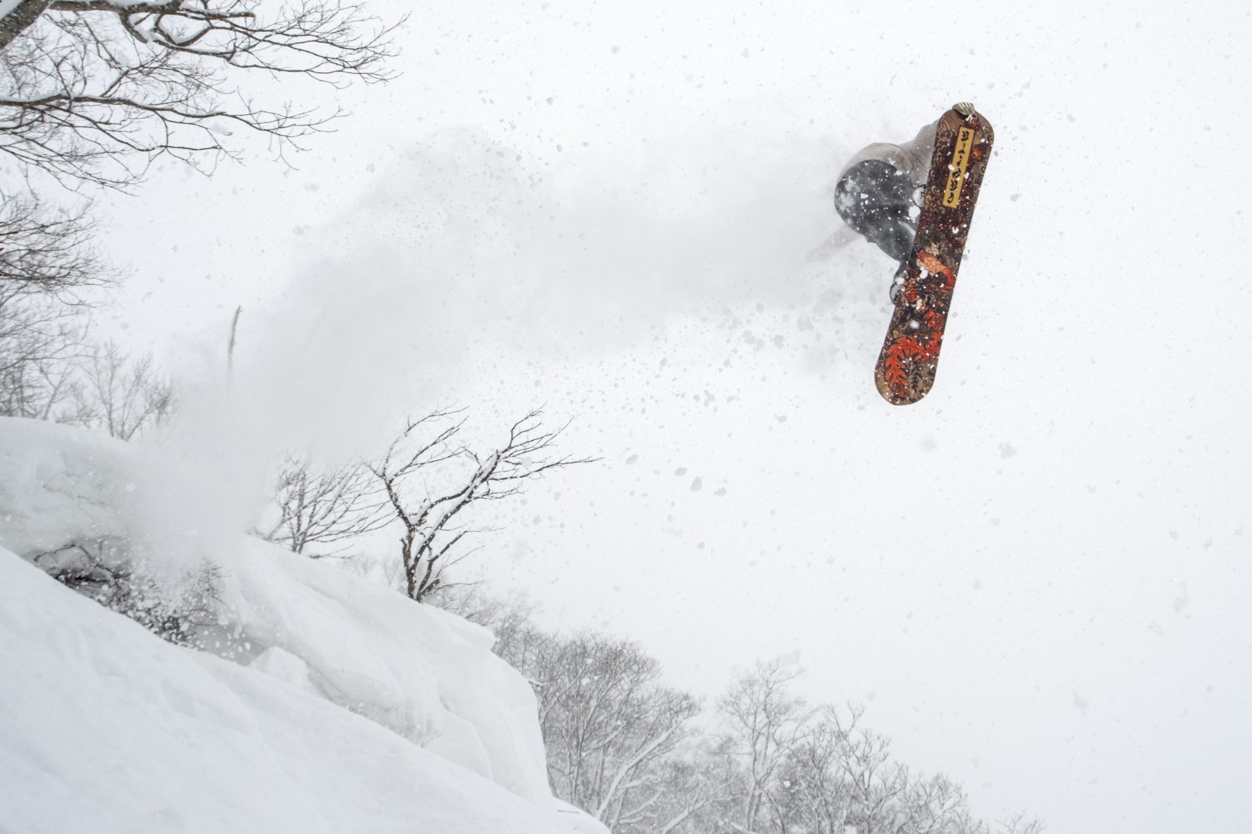 Snowboarder grabbing tail mid-air over Niseko backcountry powder