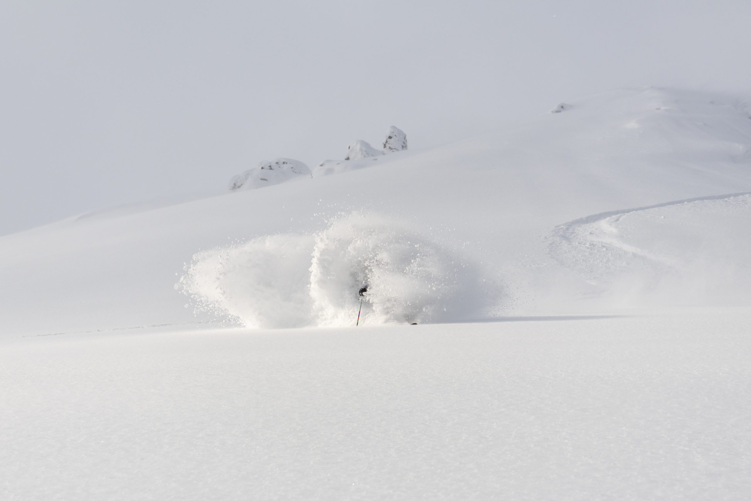 Skier disappearing into a cloud of snow on a photographed backcountry tour