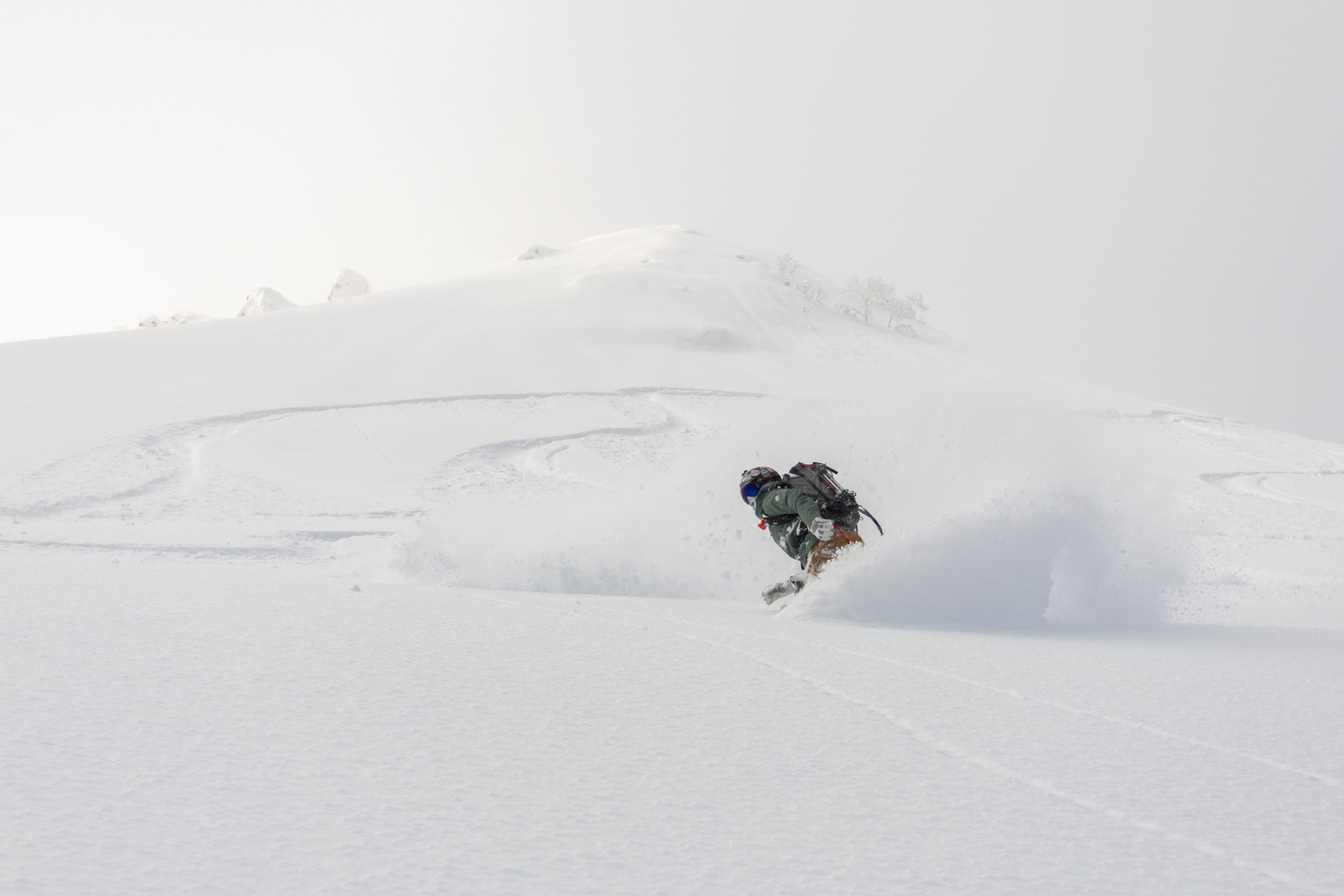 Splitboarder carving fresh snow on a guided Niseko backcountry tour