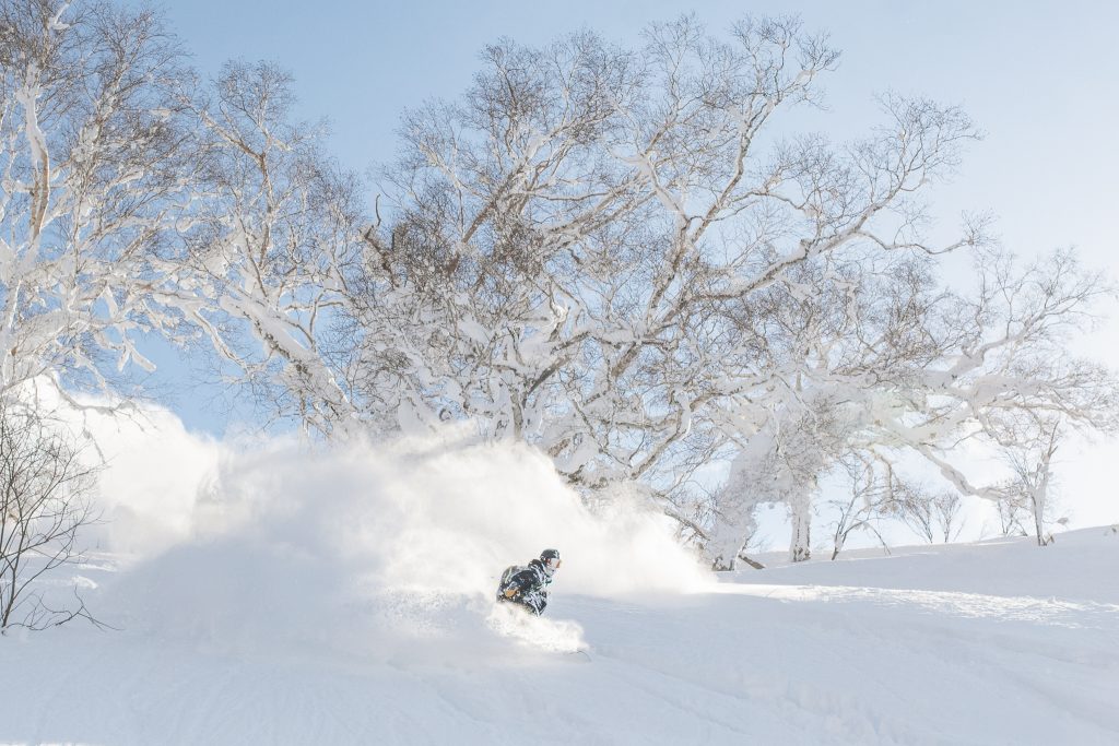 a snowboarder riding in deep niseko powder snow