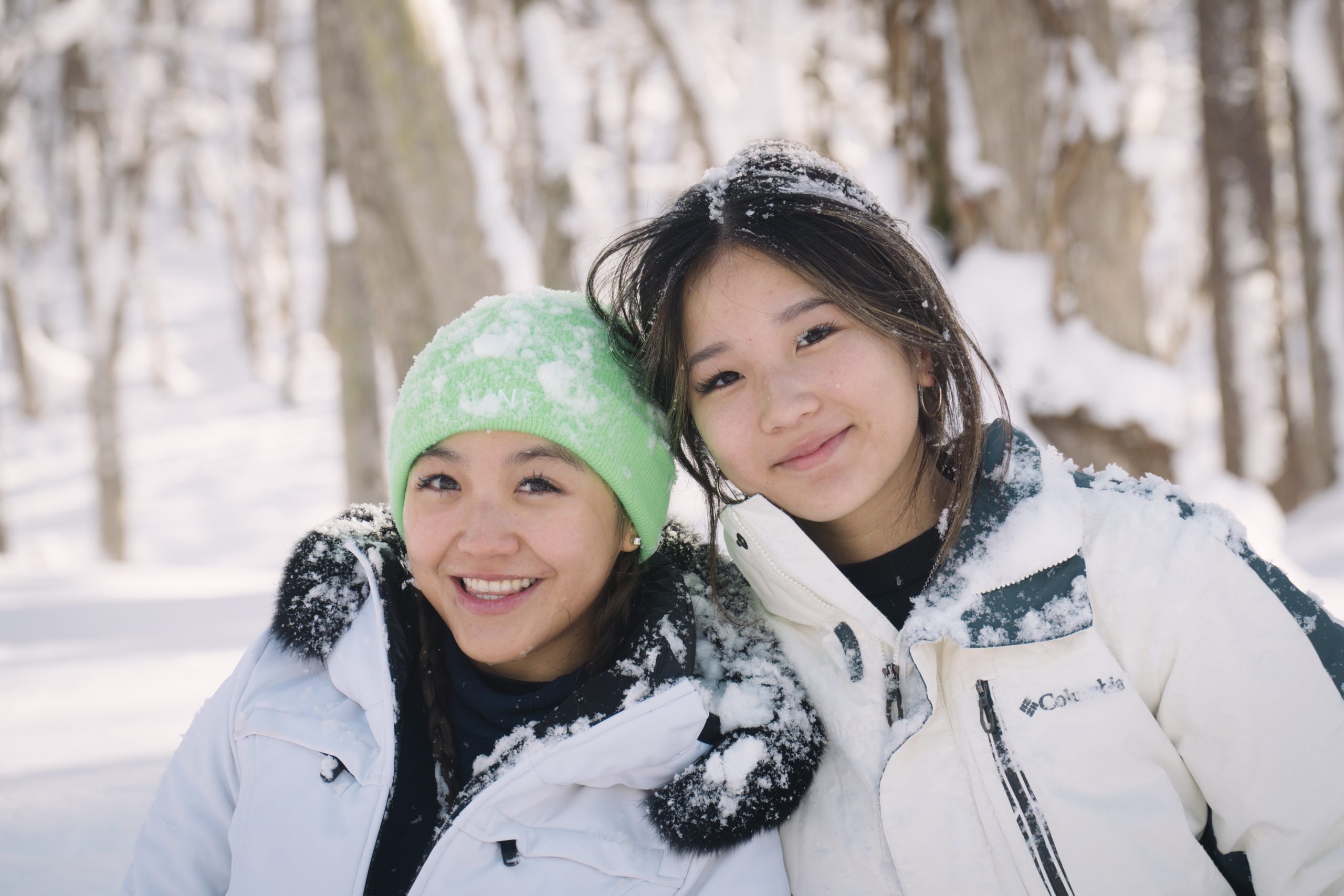 Two sisters smiling together in the snow at Annupuri