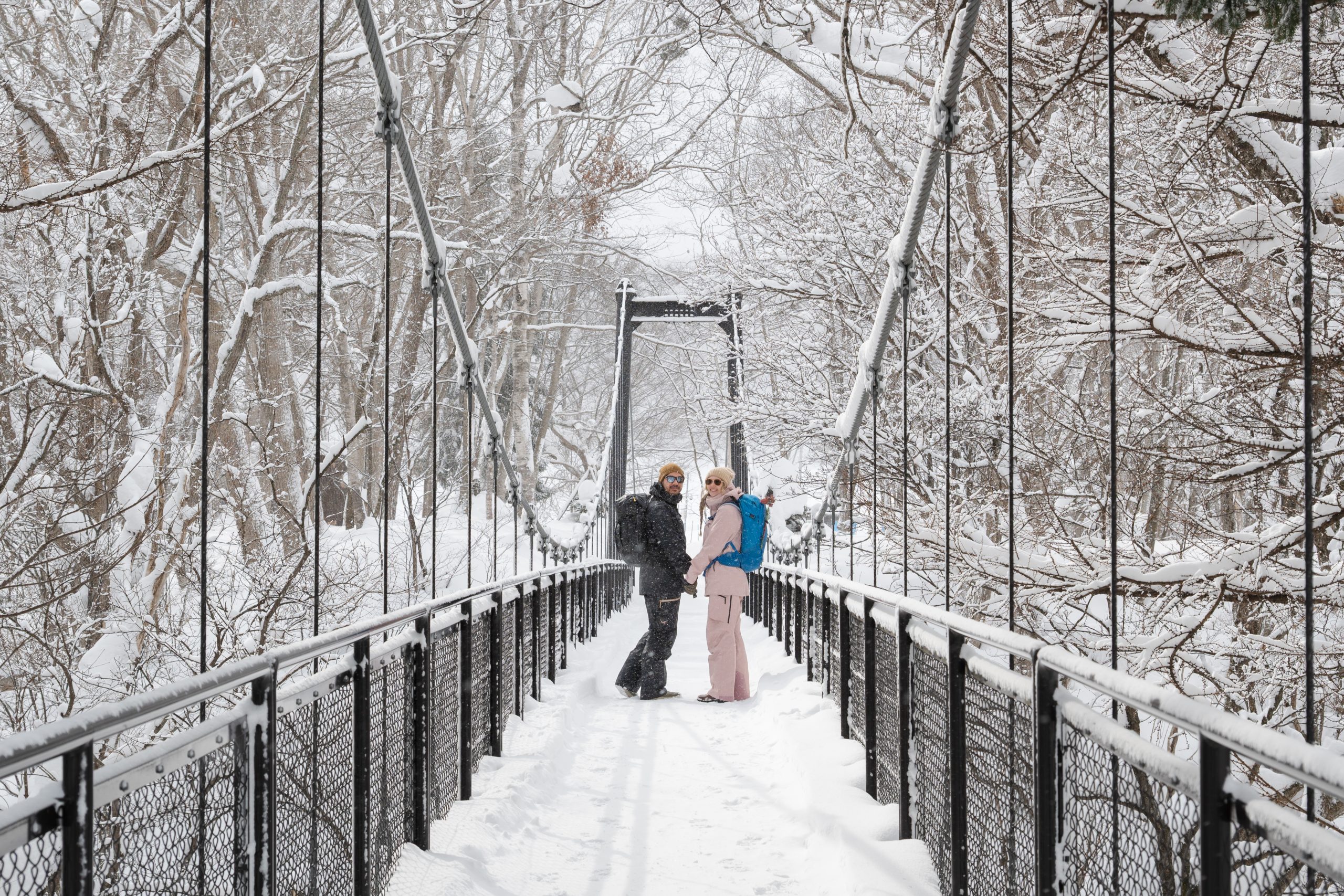 Couple on a snowy suspension bridge in a Hokkaido forest
