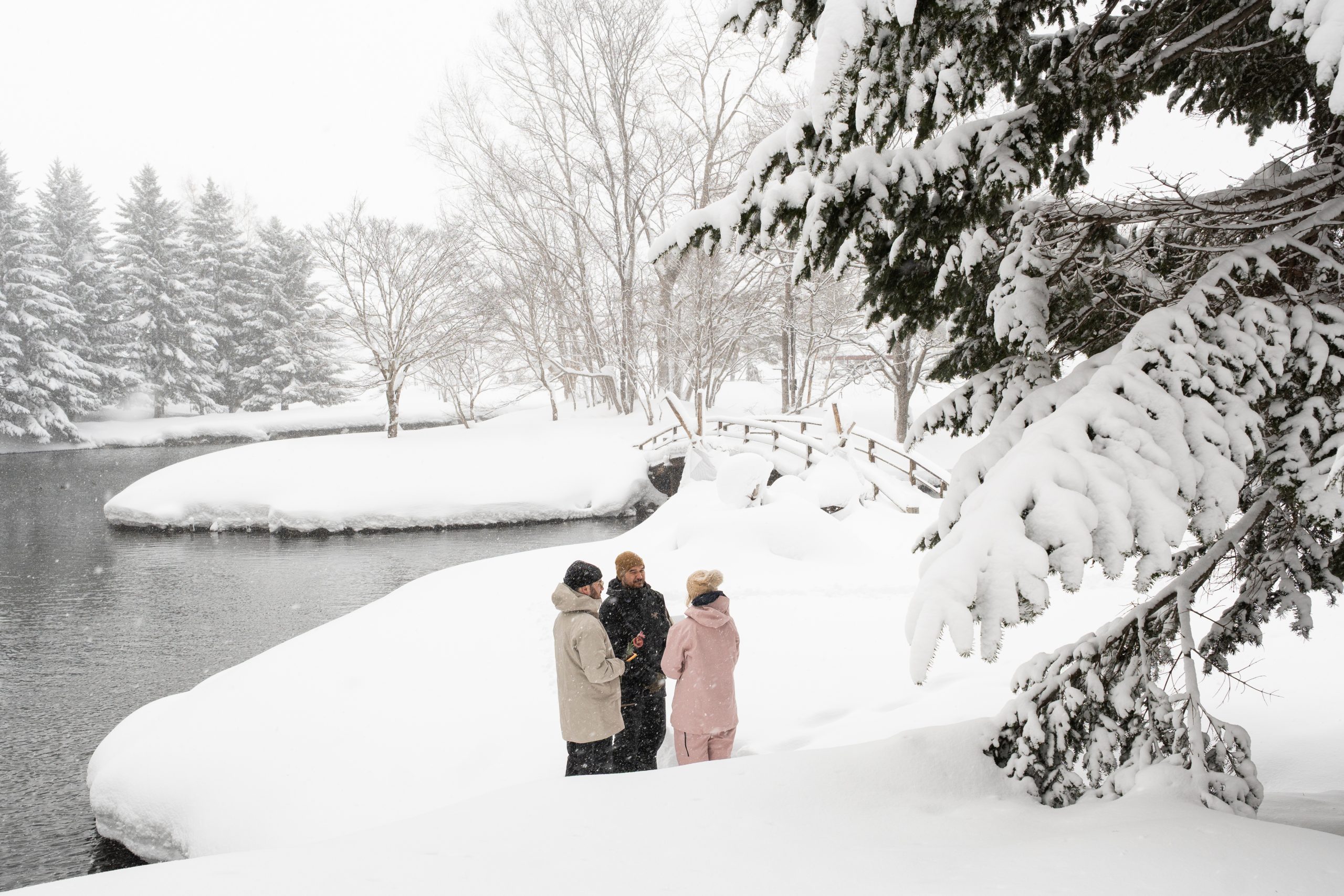 Couple standing beside a snow-covered river near Niseko