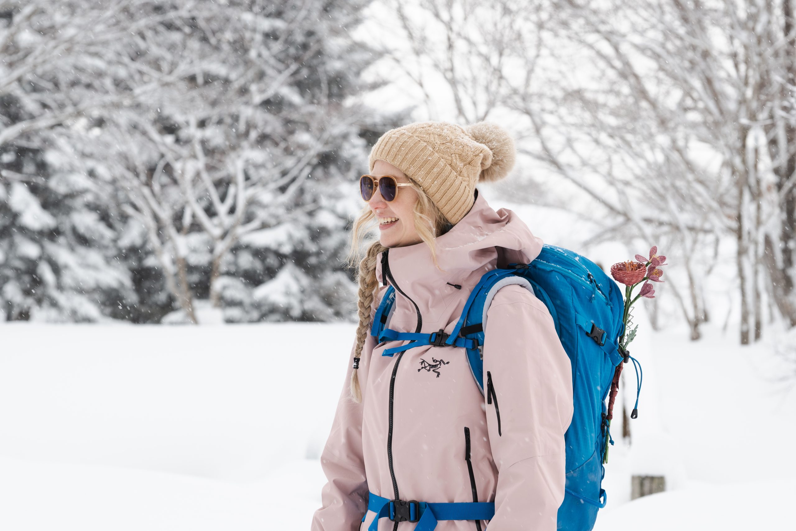 Woman smiling in the snow with a backpack on a winter walk