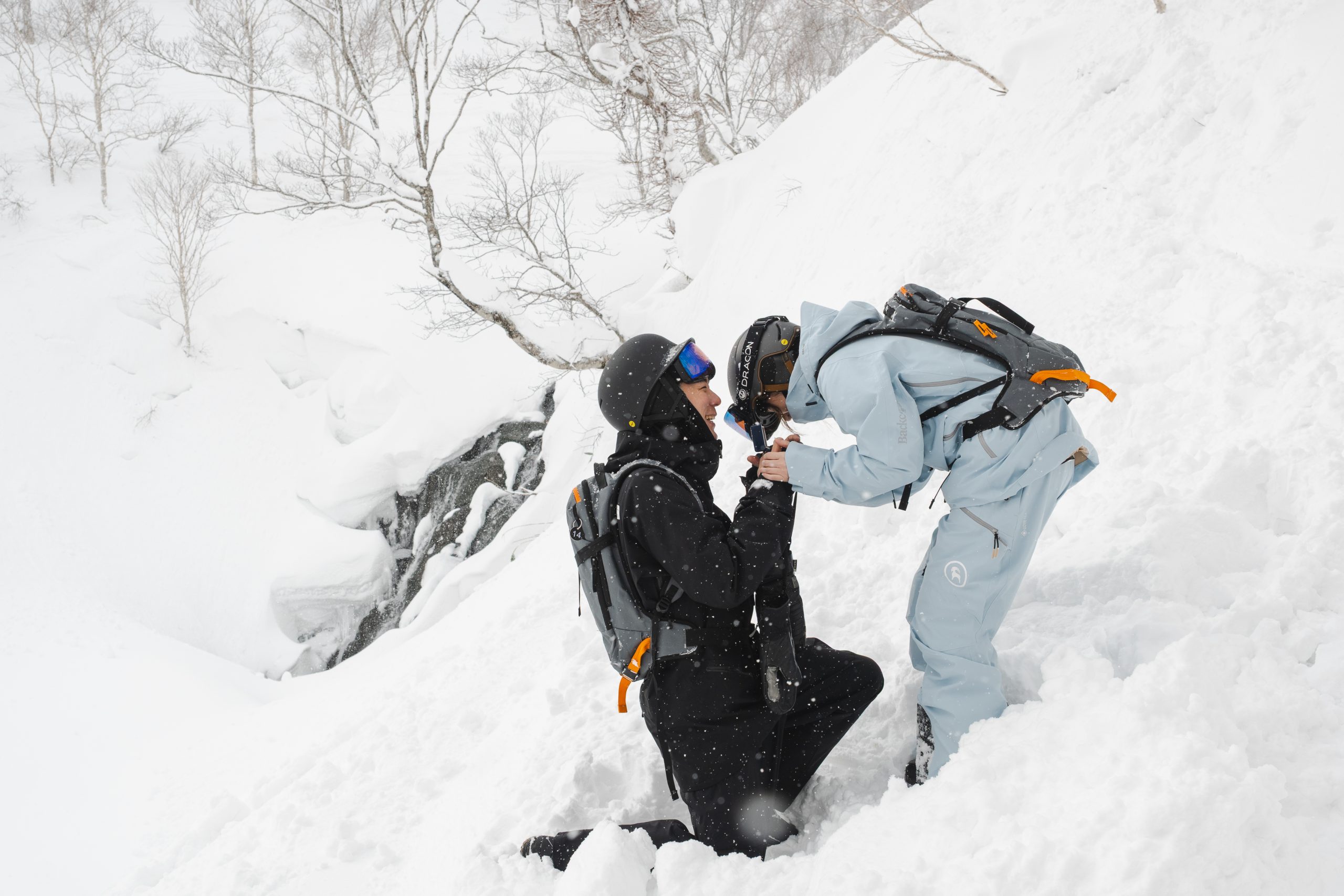 Man on one knee proposing in deep snow during a guided day in Niseko