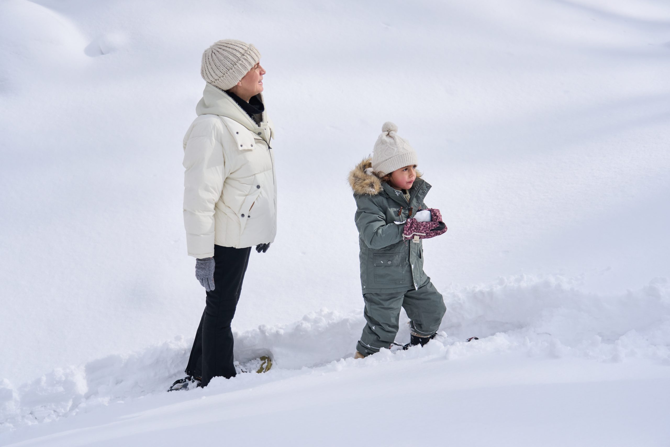 Mother and child walking through fresh snow in a Niseko forest