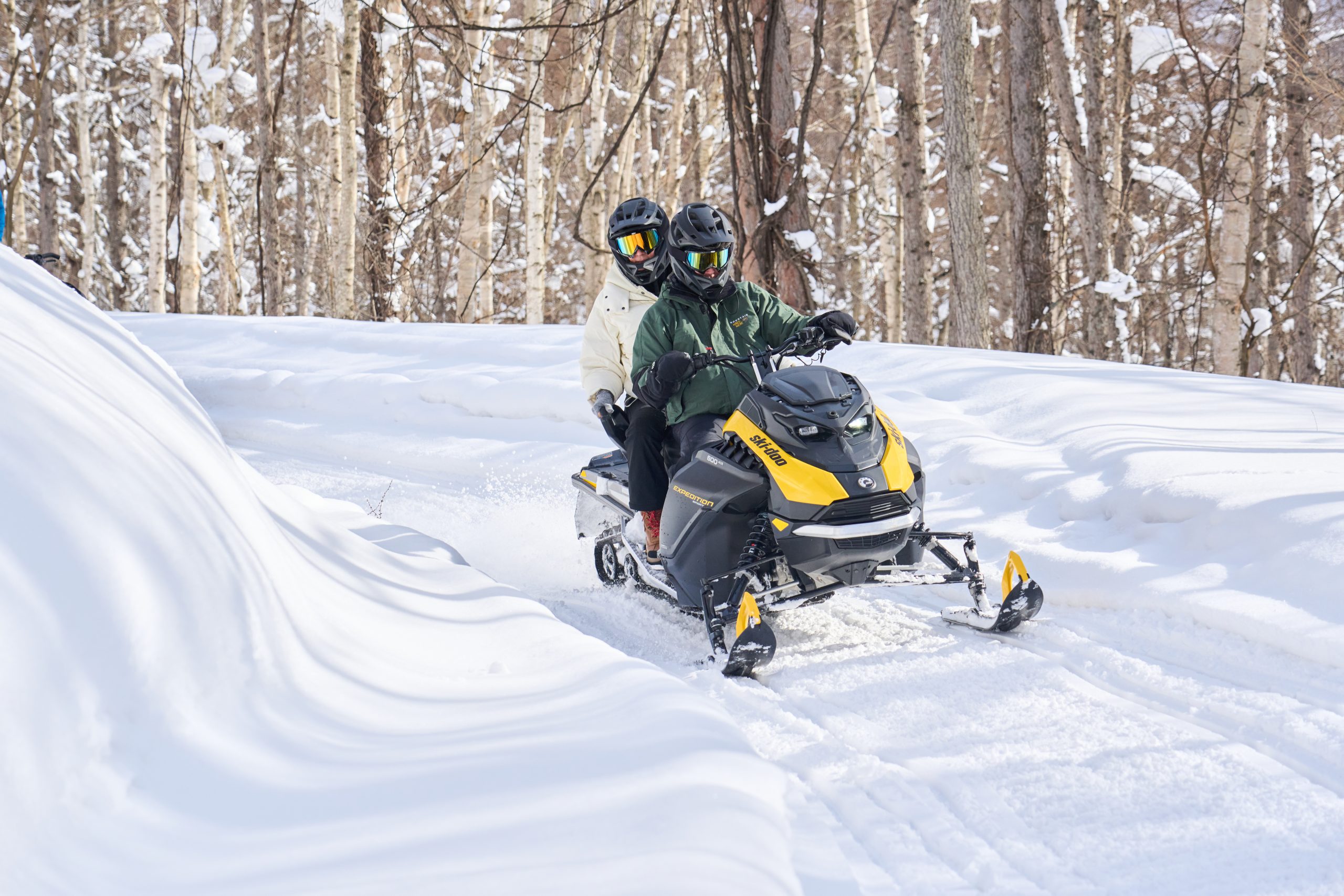 Snowmobile carving along a snow bank in the forest