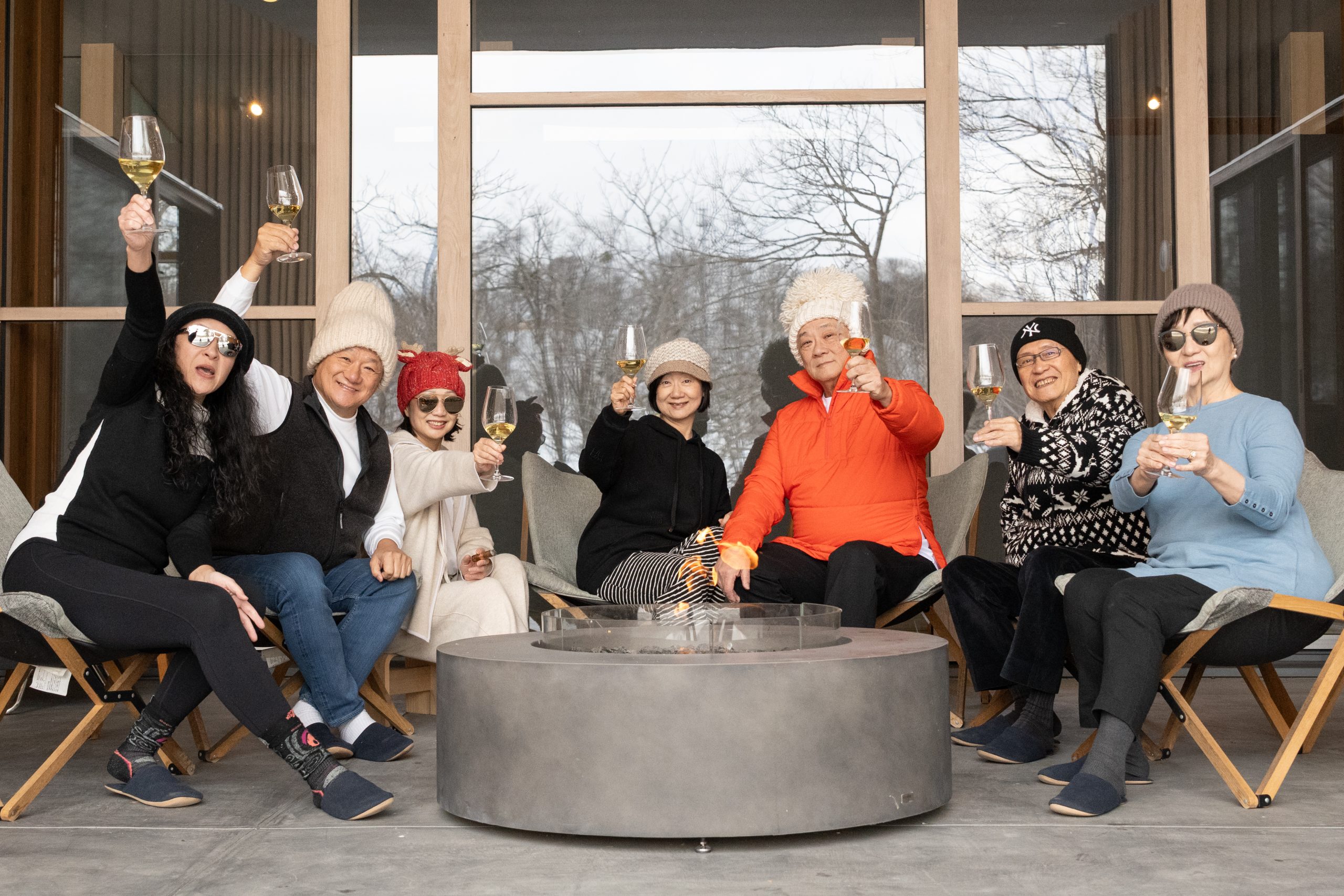 Family and friends raising a toast around a fire pit in winter