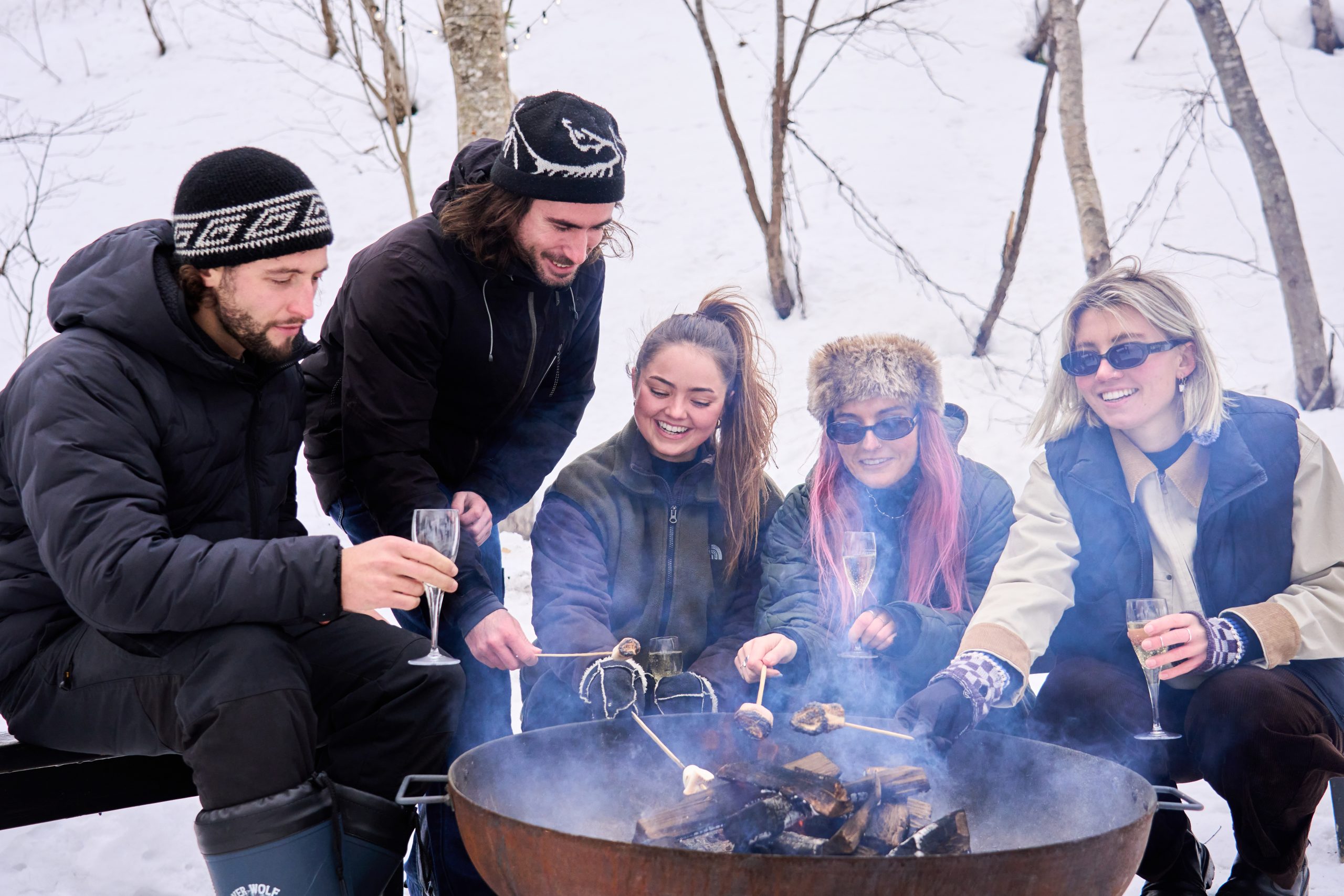Friends toasting marshmallows around the fire in the snow