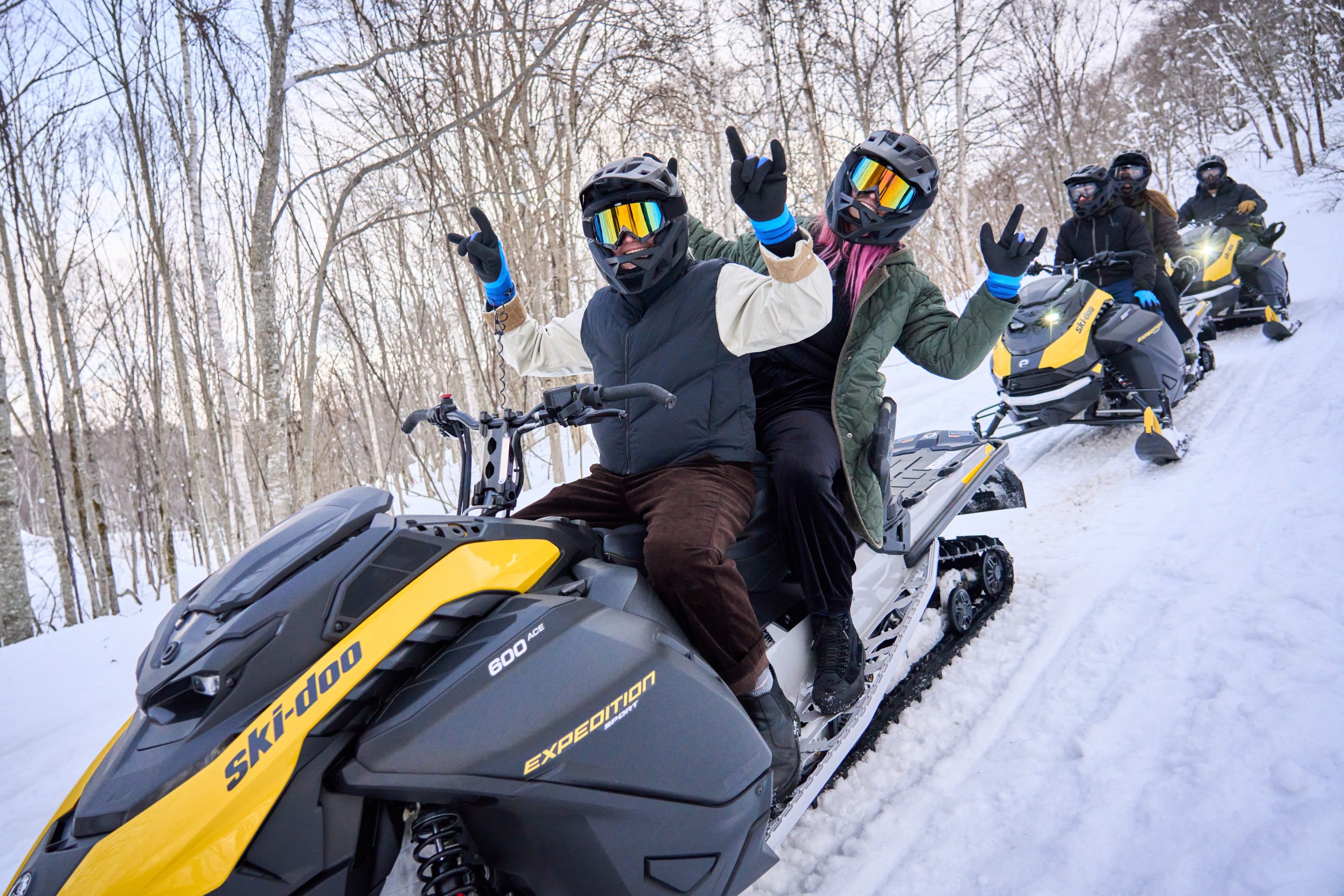 Group cheering from their snowmobiles in the forest near Niseko